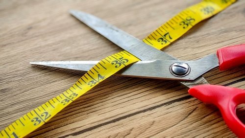Red-handled,Scissors,And,A,Yellow,Measuring,Tape,Crossing,On,A